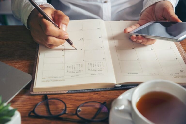 Planner plan Schedule Calendar and reminder agenda, work online at home. Women hand planning daily appointment and note holiday trip in diary at office desk. 2022 Calendar reminder event concept.