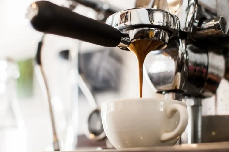 An espresso machine filling a white coffee cup