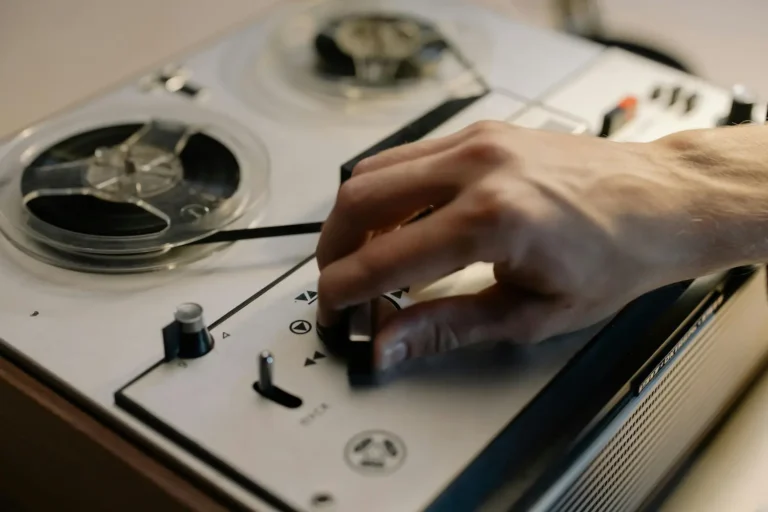 A hand adjusting an old reel-to-reel tape recorder